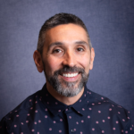 Photograph of Paul Perales. He is smiling and wearing a navy shirt.